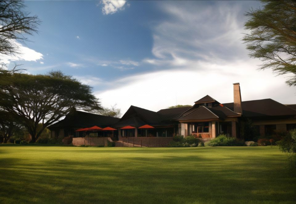 a large house with a grassy yard in front of it , surrounded by trees and grass at Muthu Keekorok Lodge, Maasai Mara, Narok