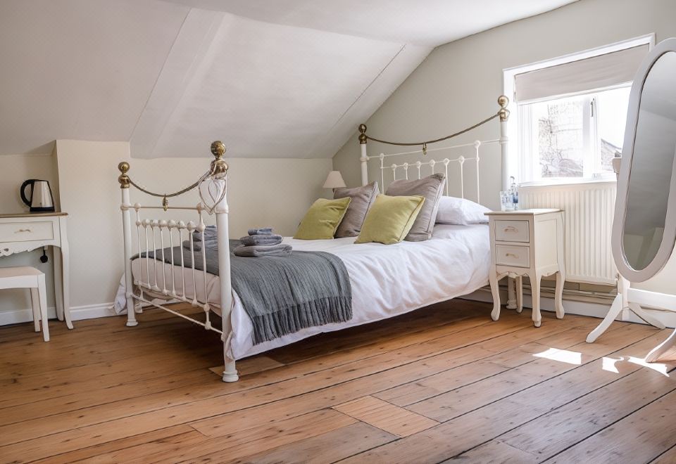 a white bedroom with a wooden floor , a white bed , and a wooden floor with a white headboard at The Golden Key