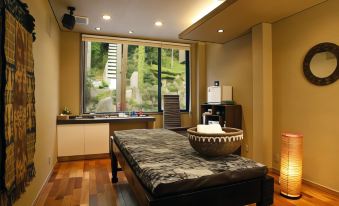 a massage table is set up in a room with a large window and a kitchenette at Fuefukigawa Onsen Zabou