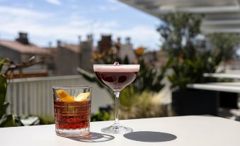 a glass of cocktail with a straw and a drink with an orange slice on the side at Okko Hotels Toulon Centre
