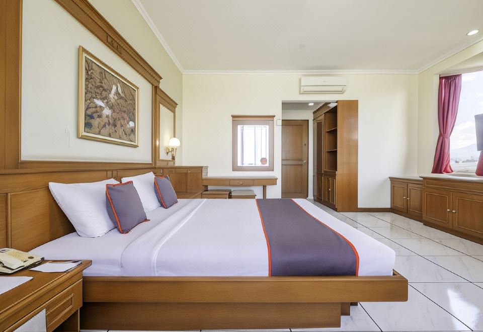 a large bed with white sheets and an orange accent is in a room with wooden furniture at Super OYO Collection O 25 Hotel Baltika