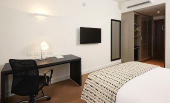 a modern bedroom with a black desk , a bed , and a flat screen tv mounted on the wall at Tulip Inn Itaguai