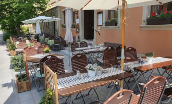 an outdoor dining area with multiple tables and chairs , some of which are covered by umbrellas at Akzent Hotel Schranne