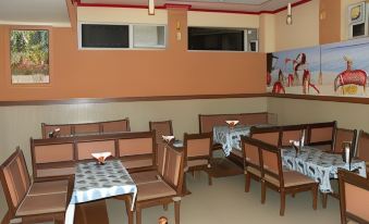 a dining area with several tables and chairs , as well as a statue of a rooster at Pinky Hotel