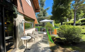 a small house with a green roof and a patio area with tables and chairs at Logis le Chalet