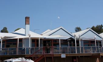 a large house with a blue roof and a white kite flying in the sky at Beauty Point Waterfront Hotel