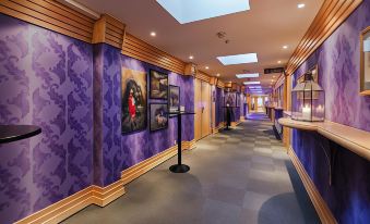 a hallway with purple walls and wooden trim , featuring several paintings and sculptures on the walls at Quality Hotel Grand Kongsberg