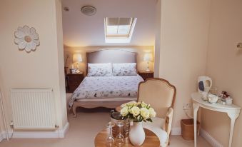 a cozy bedroom with a bed , two chairs , and a table , all lit by natural light from the skylight at Higher Farm