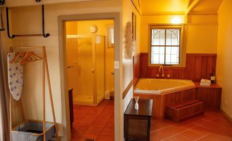 a bathroom with yellow walls and a red tiled floor , featuring a bathtub and a window at Kalimna Woods Cottages