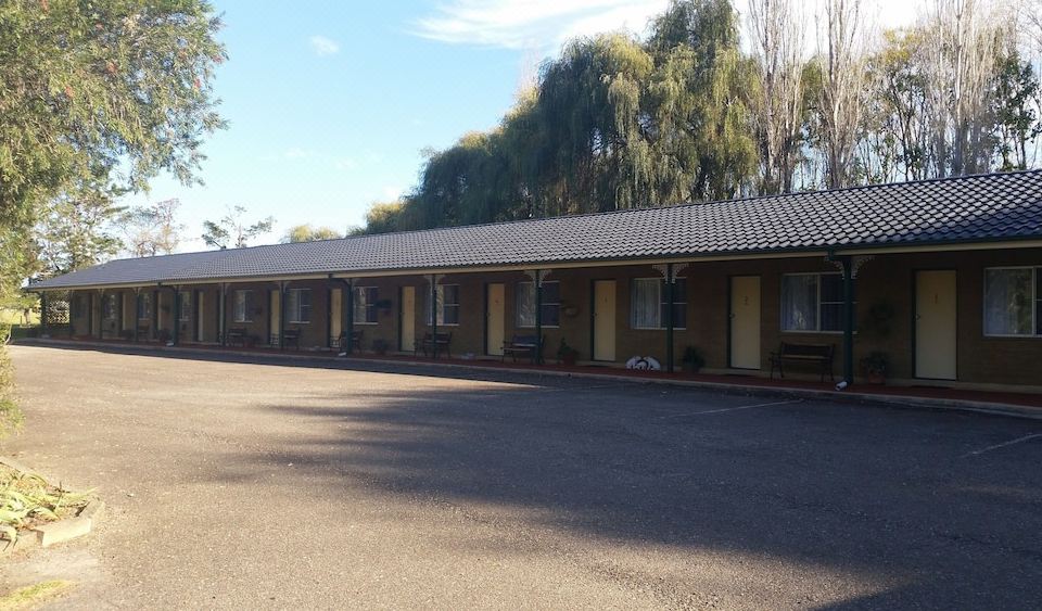 "a row of buildings with the word "" booking "" written on them , surrounded by trees and a parking lot" at Moruya Motel