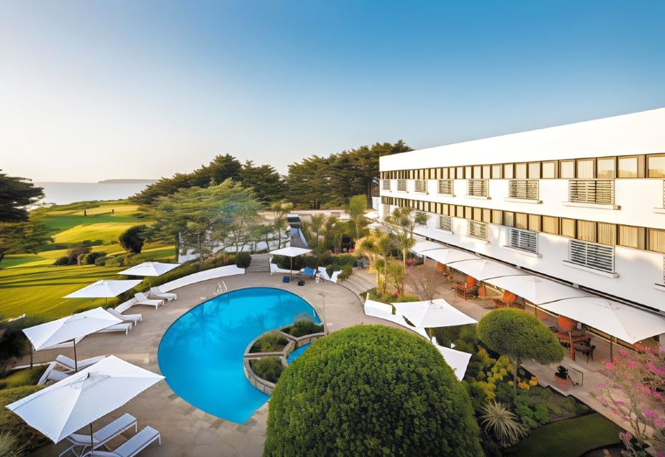 a large hotel with a pool surrounded by lounge chairs and umbrellas , providing a relaxing atmosphere at The Atlantic Hotel