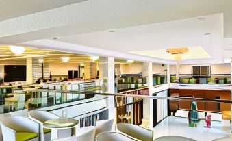 a spacious , well - lit lobby with white columns and columns , multiple seating areas , and a bar area at Tre Xanh Hotel