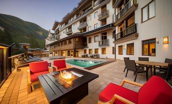 a large swimming pool is surrounded by a patio with red chairs and tables , as well as a building with balconies at The Blake at Taos Ski Valley