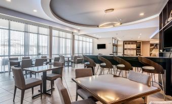 a modern , well - lit dining area with multiple tables and chairs , as well as a television mounted on the wall at SpringHill Suites Oklahoma City Downtown/Bricktown