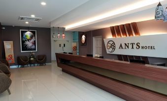"a reception area with a wooden counter and chairs , featuring the logo "" ants hotel "" on the wall" at Ants Hotel