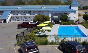 a hotel with a swimming pool and umbrellas , surrounded by a parking lot with cars at Grand Forks Inn