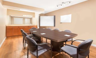 a conference room with a wooden table surrounded by chairs and a large screen on the wall at Grand Forks Inn