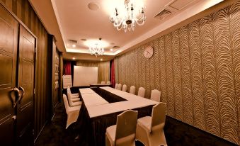 a conference room with a long table , chairs , and chandeliers , set up for a meeting at Amaroossa Hotel Bandung Indonesia
