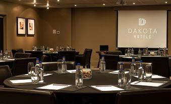 a conference room with tables and chairs , water bottles , and the dakota hotel logo on the screen at Dakota Eurocentral
