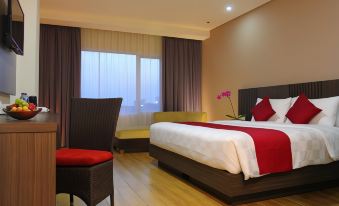 a modern hotel room with a large bed , wooden flooring , and a balcony offering views of the city at Merapi Merbabu Hotels Bekasi