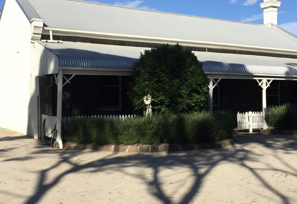 a large tree in front of a building with a white picket fence and a statue in the middle at Little River Bed and Breakfast