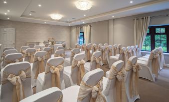 a conference room set up for a wedding or special event , with rows of white chairs and gold ribbons draped over them at The Holt Hotel