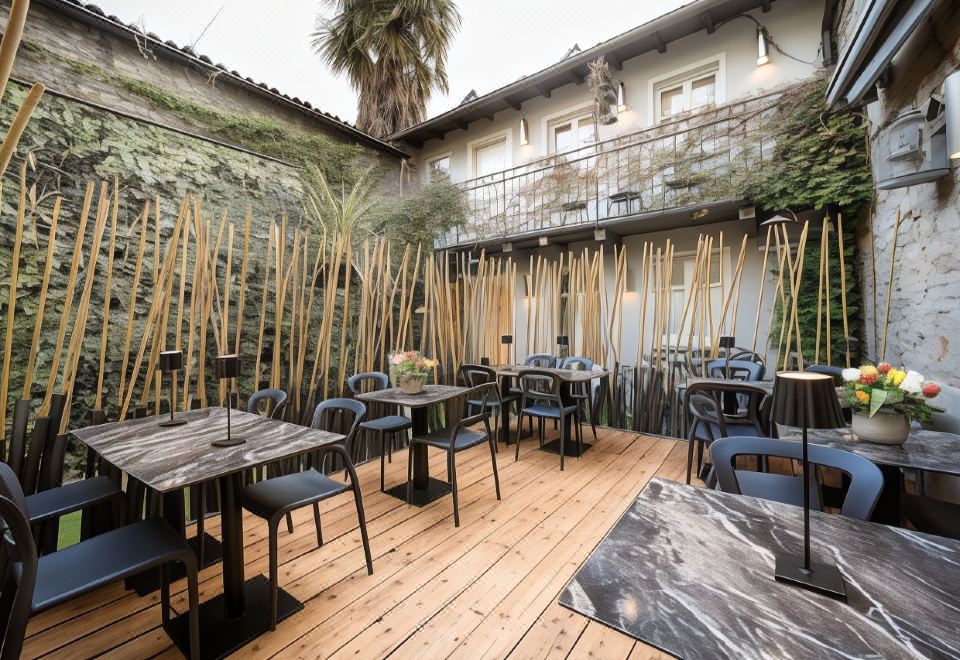 an outdoor dining area with wooden tables and chairs , surrounded by greenery and a bamboo wall at Avenue Boutique Hotel