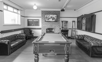 a pool table is the centerpiece of a room with couches and a fireplace in the background at The Punch Bowl