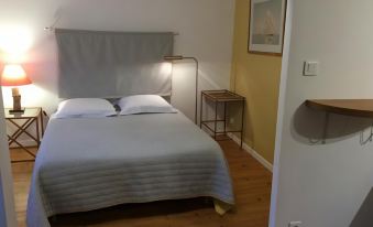 a clean and well - organized bedroom with a white bed , a mirror , and a wooden floor at La Terrasse, Centre St-Antonin