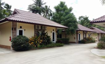 two small , white - colored houses with red roofs and green shutters , surrounded by palm trees and lush vegetation at Palm Sweet Resort