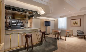 a modern , well - lit hotel lobby with a bar , dining area , and kitchenette , all connected by wooden flooring and large windows at Exe Salamanca