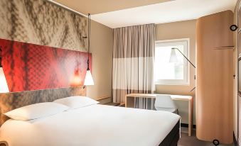 a modern hotel room with a white bed , red headboard , and a desk , along with other amenities at Ibis Lyon Villefranche-Sur-Saône