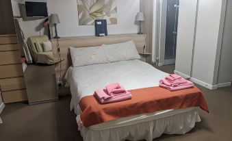 a bedroom with a white bed , two pink towels on the bed , and a tv mounted on the wall at Cwmbach Guest House
