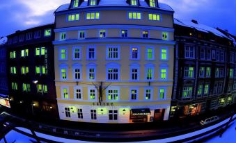 a building with multiple floors and green lights is surrounded by other buildings in the city at Hotel Sailer