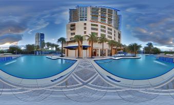 a large building with a swimming pool in front of it , surrounded by palm trees at Marriott's Oceana Palms