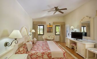 a large bedroom with a bed , dresser , and tv . also a chair in the room at Bahia Principe Grand Cayacoa