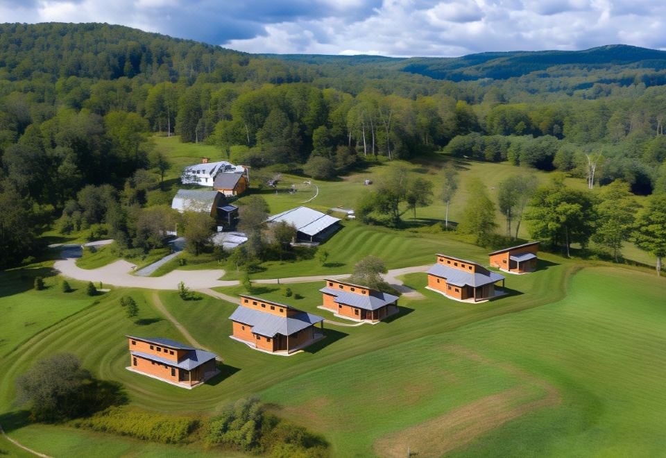 aerial view of a golf course surrounded by green grass and buildings , with trees in the background at Fat Sheep Farm & Cabins