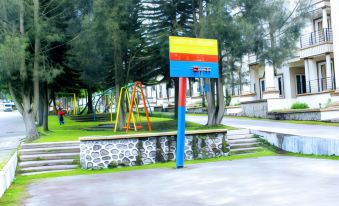 a colorful playground with various play structures , such as swings , slides , and climbing structures , situated in a park - like setting at Villa Berastagi Highland