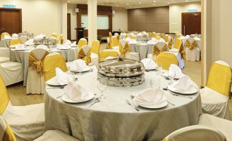 a large banquet hall with multiple round tables covered in white tablecloths and chairs arranged around them at Jewels Hotel