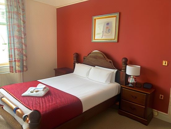 a red bedroom with a white bed , a nightstand , and a painting on the wall at The Shakespeare Deluxe Hotel and Caribbean Restaurant Halifax