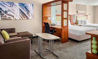 a hotel room with a bed , desk , and couch , as well as a painting on the wall at SpringHill Suites Long Island Brookhaven