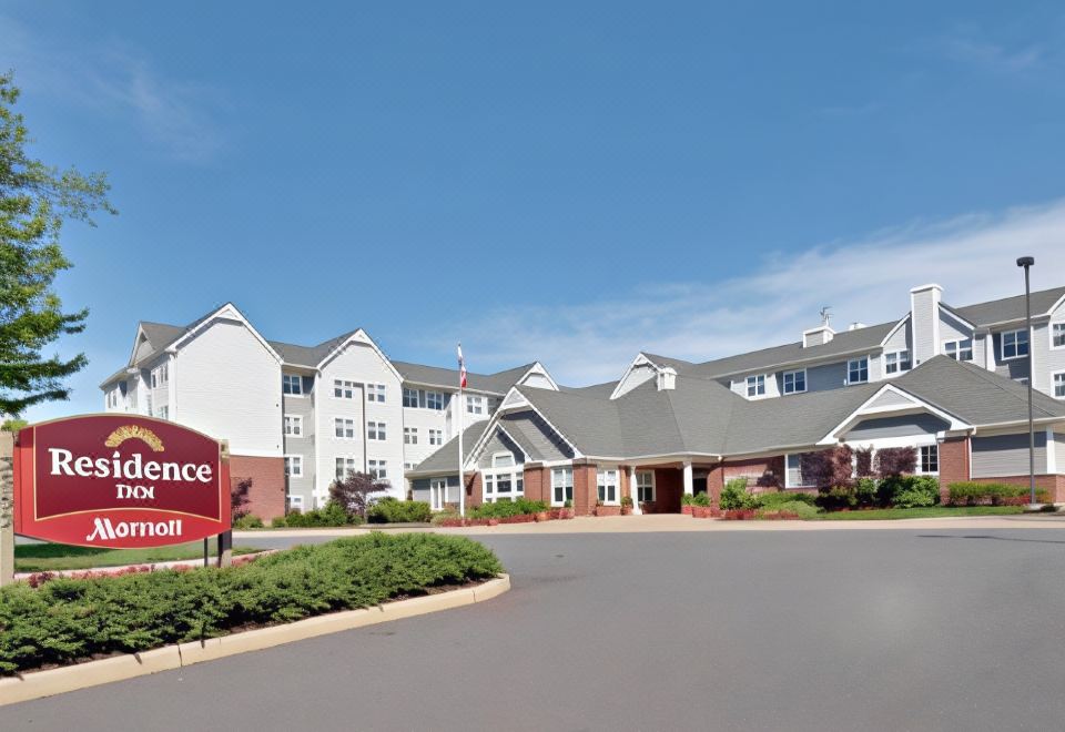 "a large hotel with multiple buildings , including a "" reliance "" sign in the foreground , surrounded by green grass and trees" at Residence Inn by Marriott Princeton at Carnegie Center