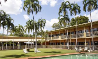 a tropical resort with palm trees , swimming pool , and white loungers under a clear blue sky at Litchfield Outback Resort