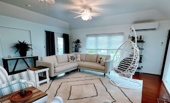 a modern living room with a white couch , wooden floor , and hanging chair , surrounded by windows at Seven Arches