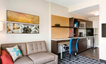a modern living room with a couch , chairs , and a desk in the background , connected to a kitchenette area at TownePlace Suites Milwaukee Grafton