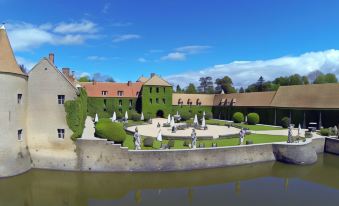 a large courtyard with a pond surrounded by green bushes , creating a serene and picturesque scene at Château de Villiers-Le-Mahieu
