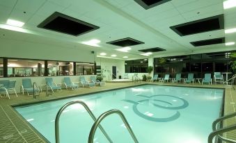an indoor swimming pool with several lounge chairs and a few people in the background at DoubleTree by Hilton Chicago - Oak Brook