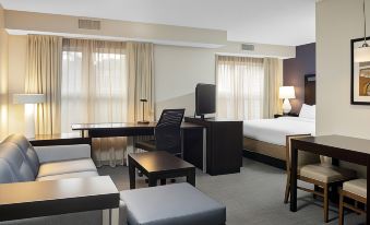a modern hotel room with a bed , desk , and couch , along with other furniture such as chairs and lamps at Residence Inn Boston Foxborough