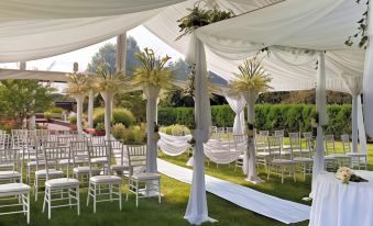 a white tent with chairs and drapes is set up in a garden , offering an elegant outdoor wedding venue at Westminster Hotel