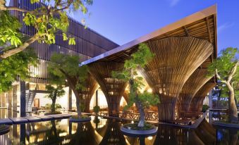 a modern building with a wooden structure and a large pool of water in front at Indochine Hotel